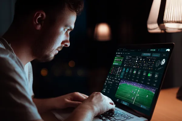 A man focused on his laptop with live stats in the background, highlighting the dedicated sports and gaming features of the WA777PK mobile app.