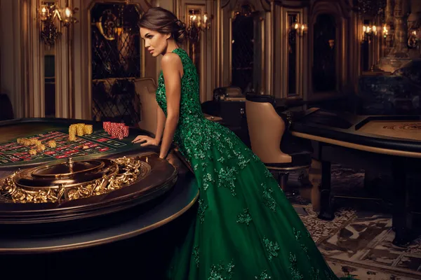 A woman in a luxurious green gown next to an ornate roulette wheel, capturing the upscale casino mood of WA777PK.
